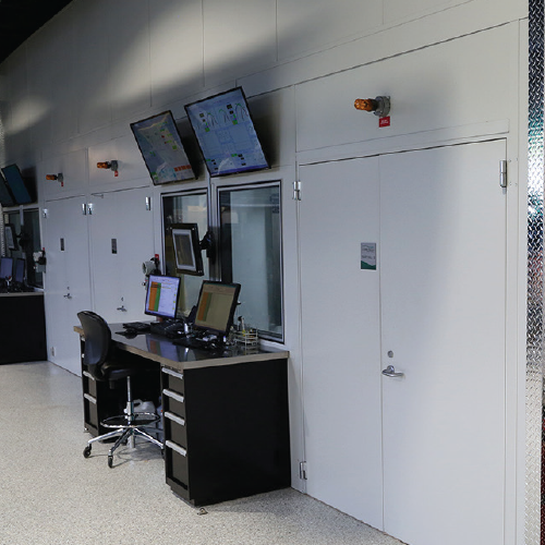 Modern control room with multiple screens and workstation in an industrial setting.