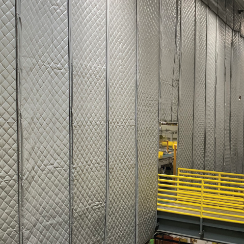 Industrial warehouse interior with quilted insulated wall panels and yellow safety railing.